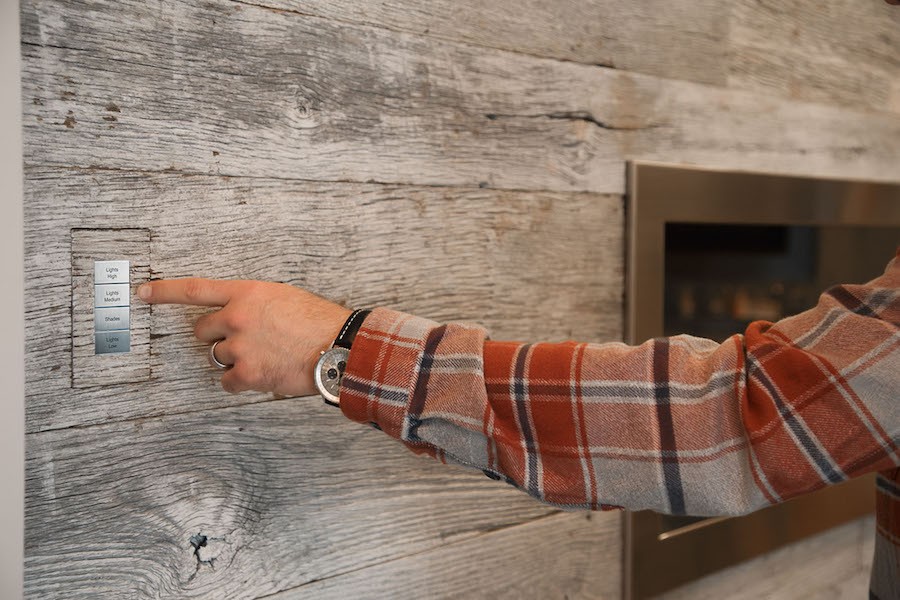 A man’s hand reaching for a custom Lutron Palladiom lighting control keypad in a Denver home.
