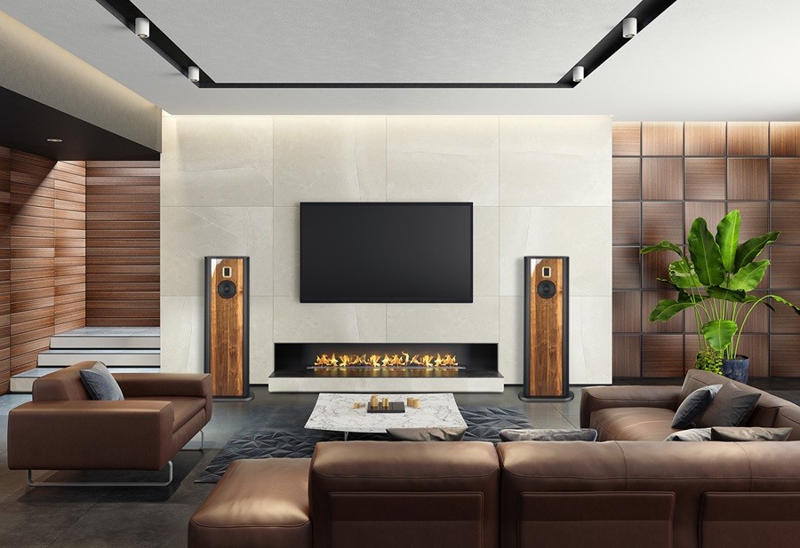 A modern living room with a fireplace, flanked by two tall wooden speakers, a mounted flat-screen TV, and comfortable leather furniture.