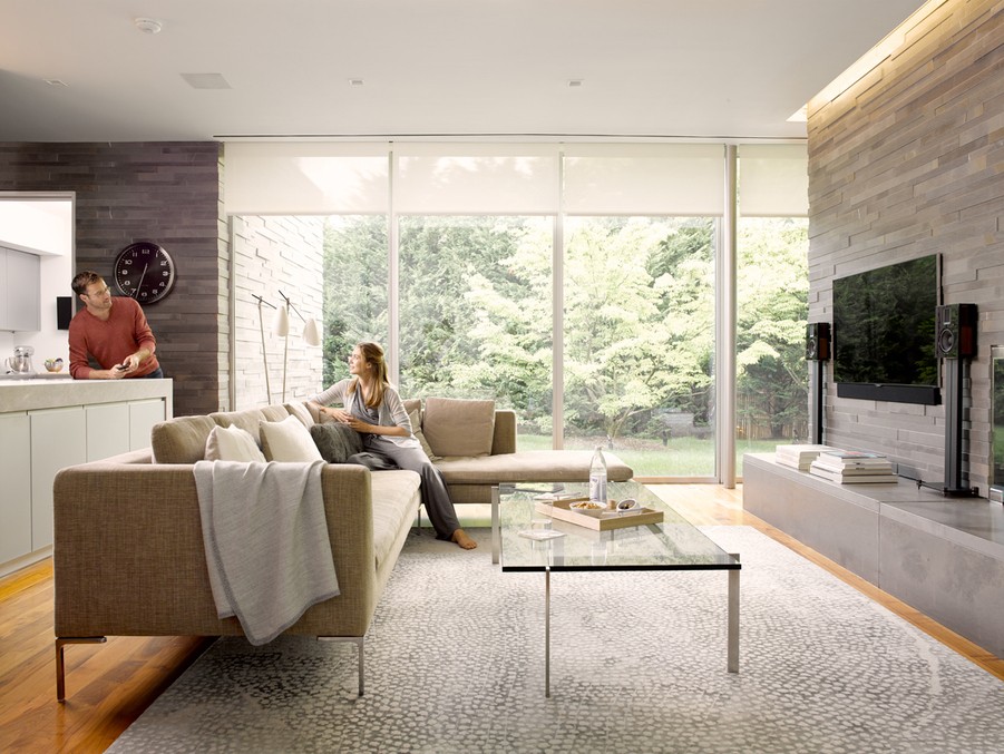 A modern living room in Colorado Springs with Savant home automation, featuring large windows overlooking greenery.
