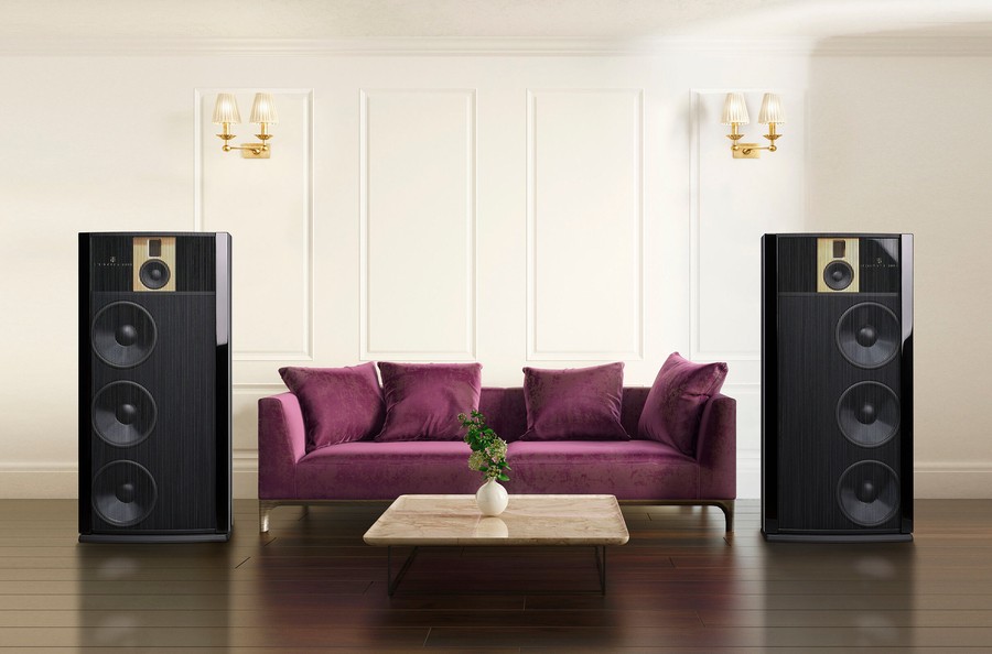 Elegant home audio setup in Denver with towering black speakers flanking a plush purple sofa, blending high-end sound with modern décor.