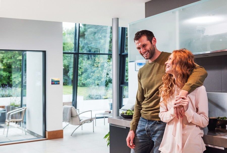 A couple stands in the kitchen of a modern Vail home managed by smart home automation. 