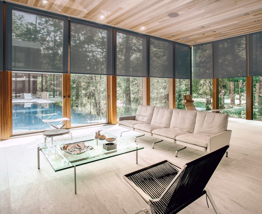 Luxurious living room with motorized shades and windows overlooking a pool area. 